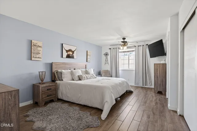 a bedroom with a large bed a flat tv screen and dresser