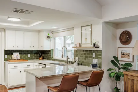 a kitchen with stainless steel appliances granite countertop a stove a sink a dining table and chairs