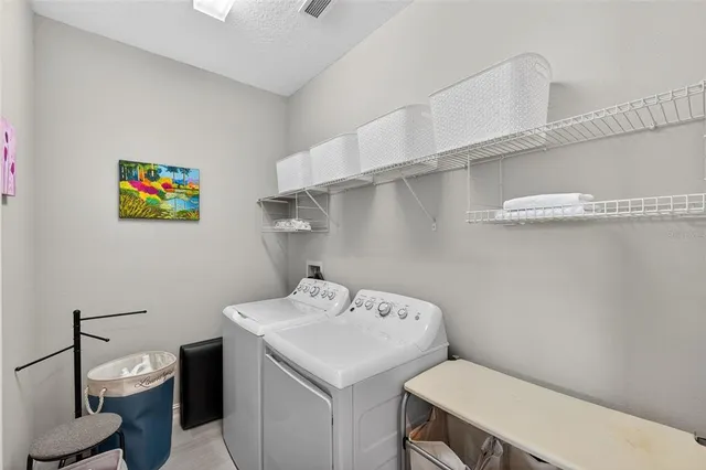 a view of a brick house with a large windows and a yard with plants and large trees