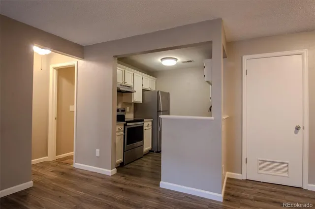 a view of a kitchen with a refrigerator a stove top oven and wooden floor