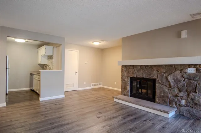 a view of an empty room with wooden floor and a fireplace