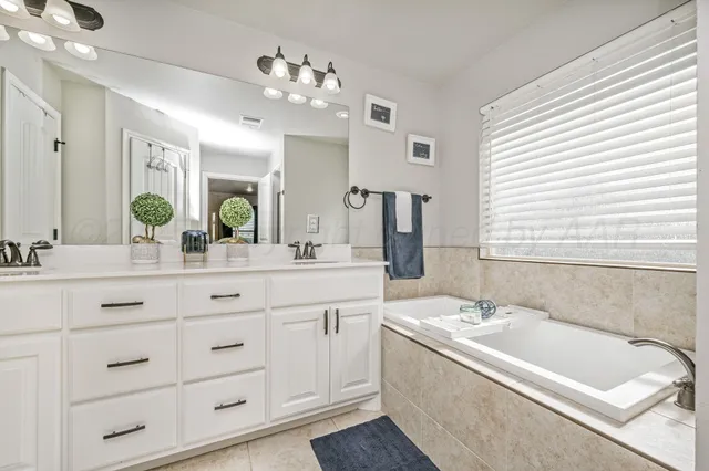 a bathroom with a double vanity sink mirror and bathtub