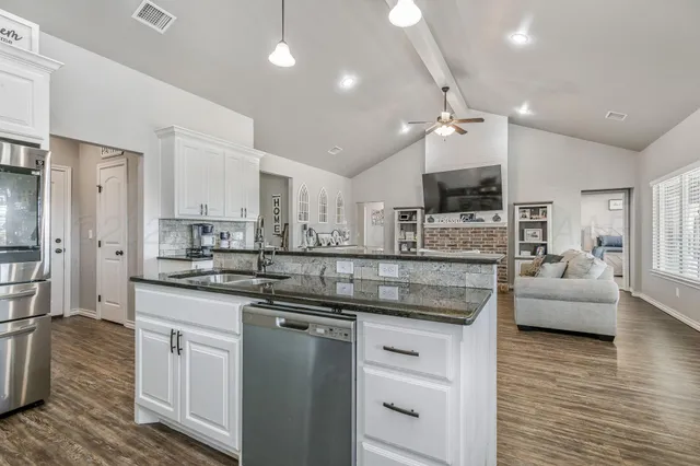 a kitchen with stainless steel appliances granite countertop a sink a stove and cabinets