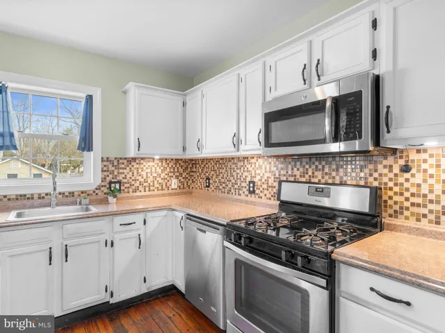 a kitchen with cabinets appliances a sink and a window