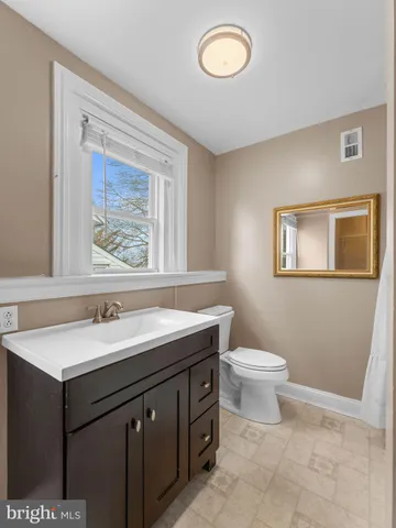 a bathroom with a granite countertop sink a mirror and a toilet