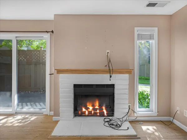 a view of an empty room with wooden floor and a fireplace