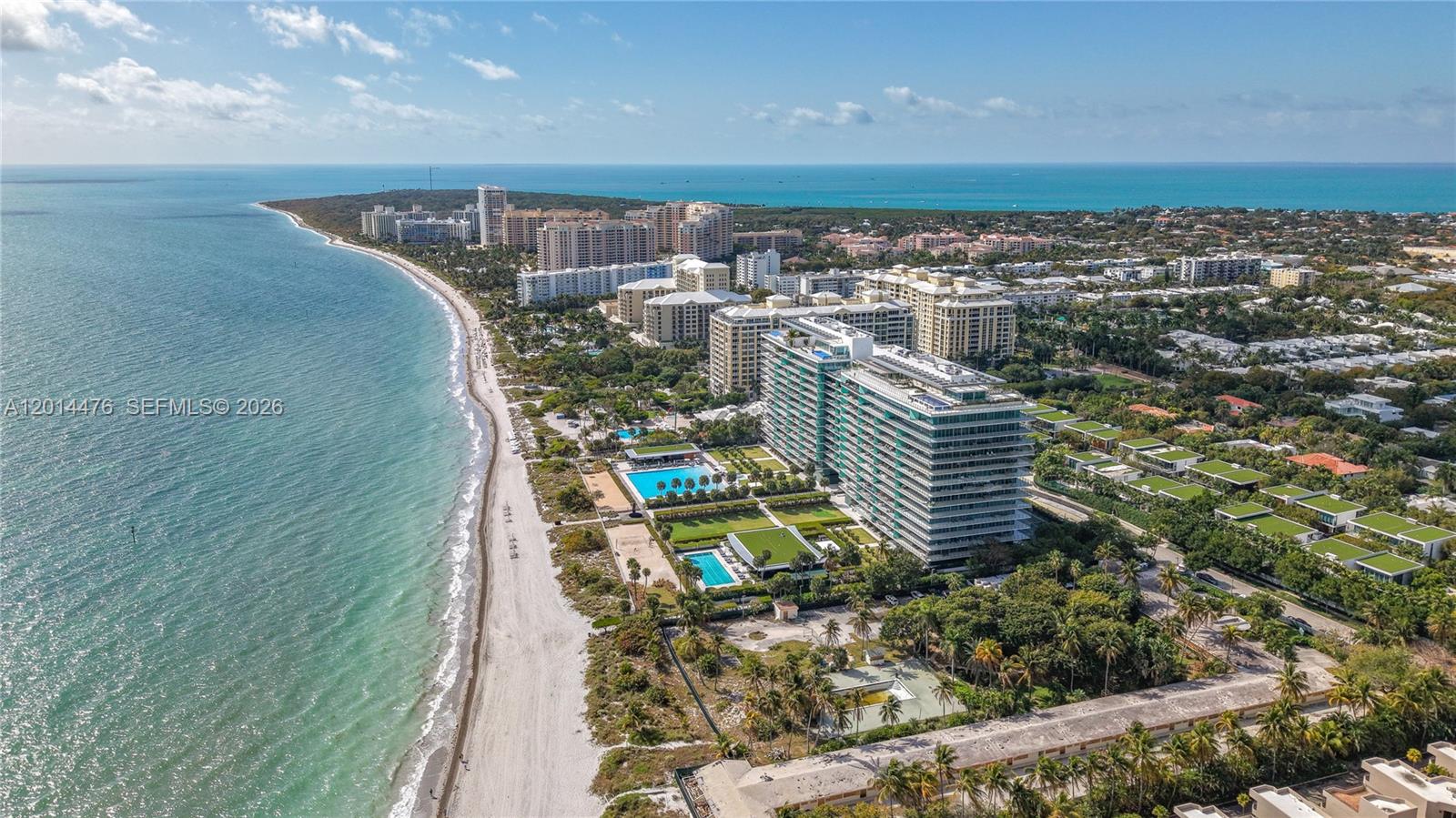 360 Ocean Drive, Unit 1106S Key Biscayne, FL 33149 - Photo 51 of 67 Aerial Coastline View – This wide aerial captures the building, beach, and turquoise water from above, with nearby residences and lush greenery extending inland. The view emphasizes the property’s premier coastal position and expansive beachfront surroundings.
