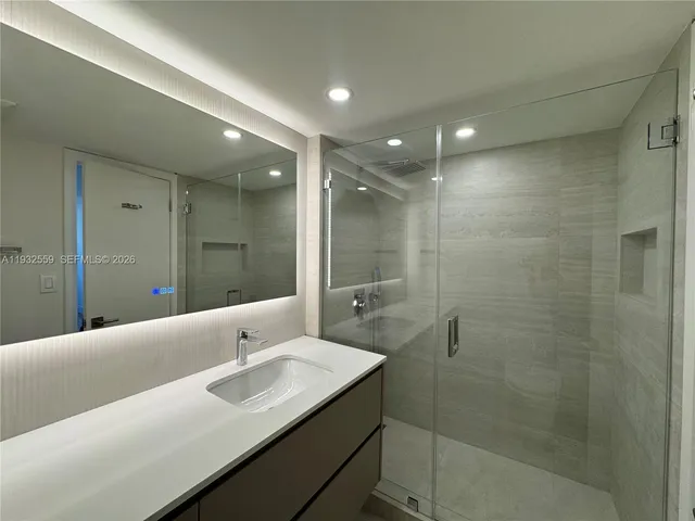 a bathroom with a sink shower and a mirror