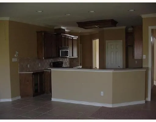 a living room with stainless steel appliances kitchen island granite countertop a refrigerator and a sink