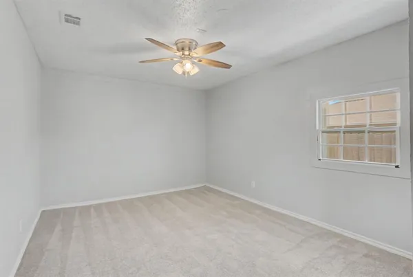 an empty room with windows and fan