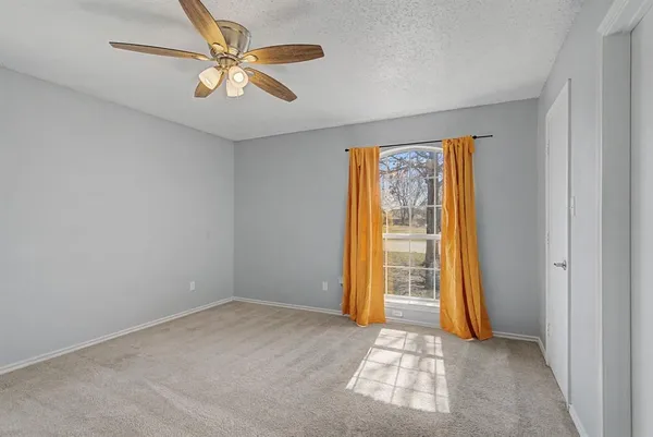 an empty room with windows and ceiling fan