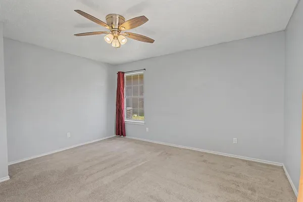 an empty room with a window and a fan