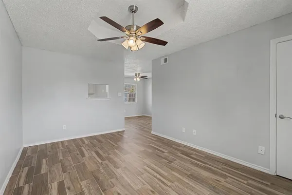 an empty room with wooden floor fan and windows