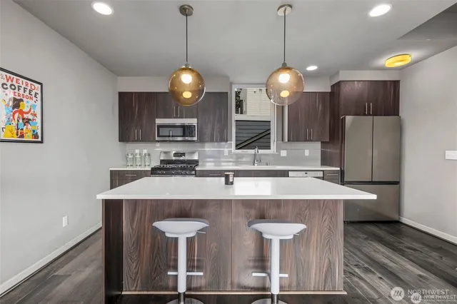 a kitchen with stainless steel appliances granite countertop a sink a microwave a refrigerator and a stove