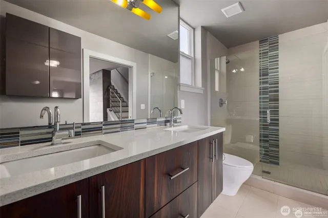 a bathroom with a double vanity sink toilet and shower