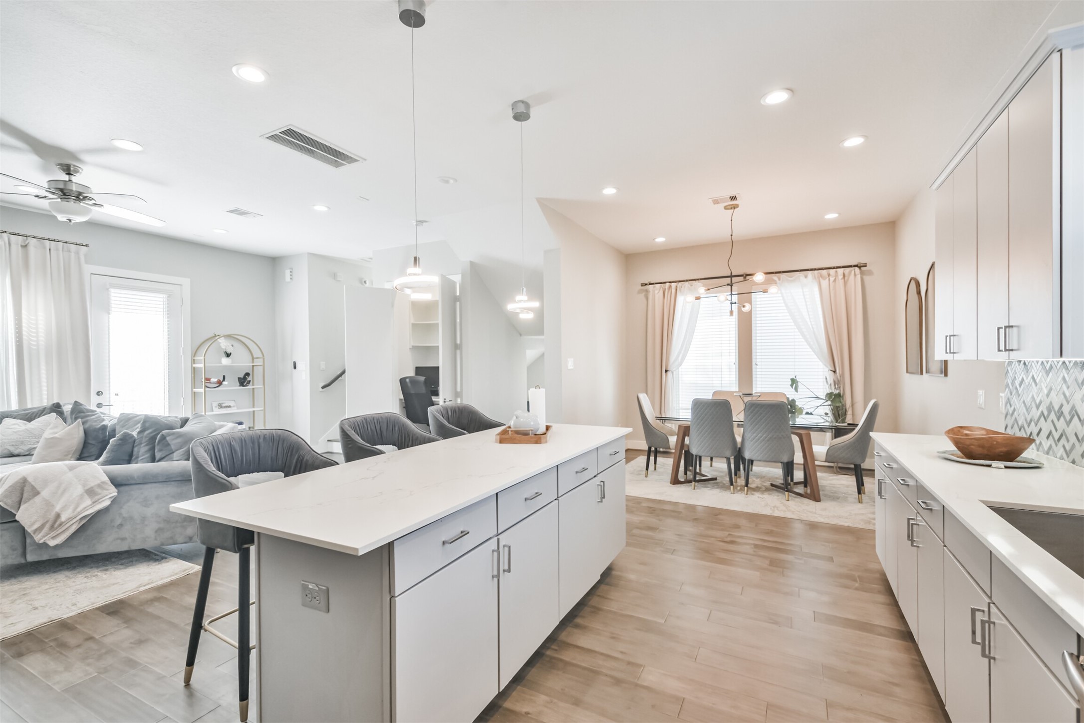 8411 Hempstead Road, Unit H Houston, TX 77008 - Photo 19 of 40 The kitchen features sleek, white cabinetry, a spacious island with bar seating, and stainless steel appliances.