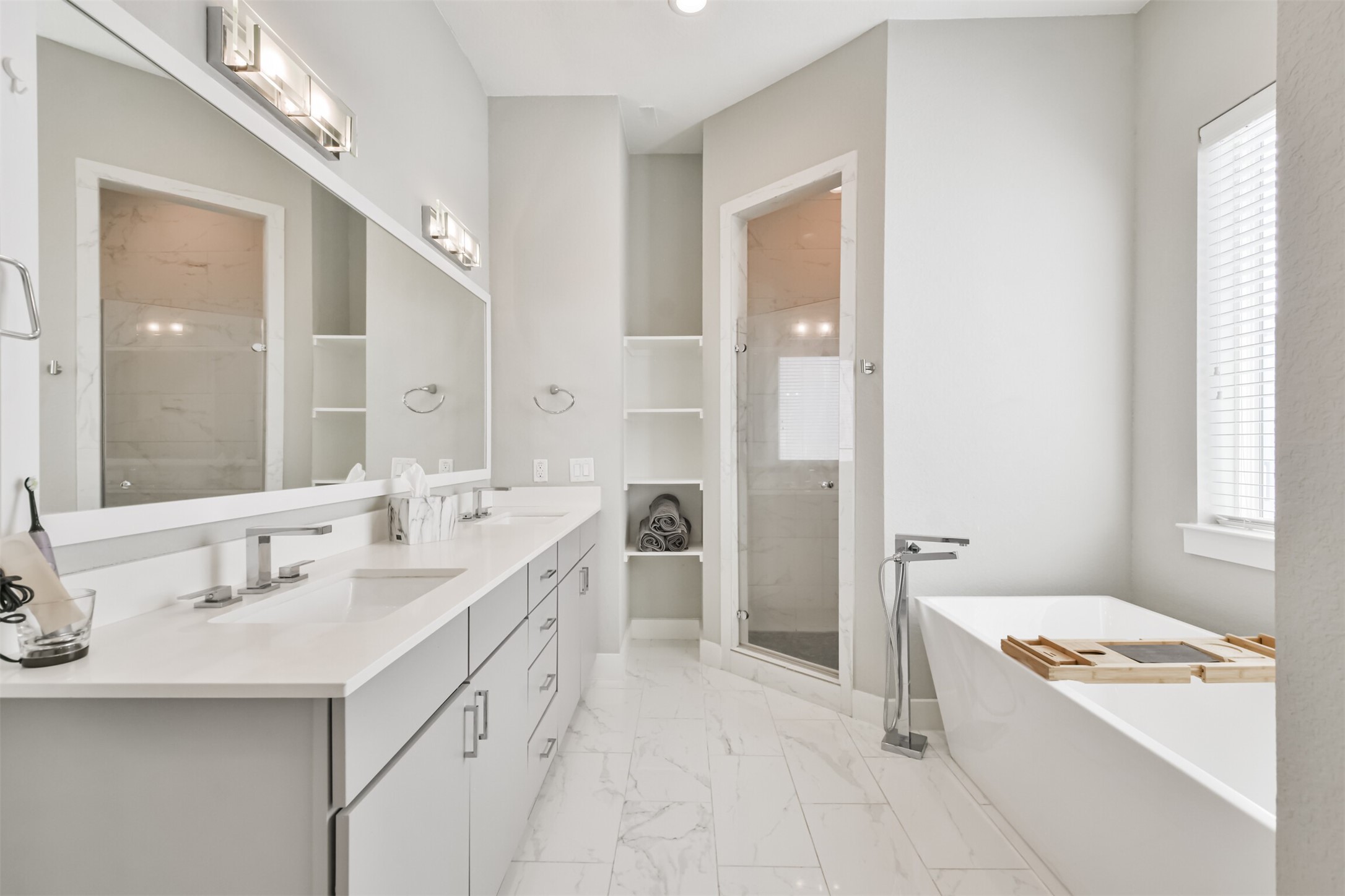8411 Hempstead Road, Unit H Houston, TX 77008 - Photo 36 of 40 A luxurious primary bathroom featuring a stunning, oversized mirror with an elegant frame, a sleek double vanity and a floor with beautiful tiles adding texture and visual interest.
