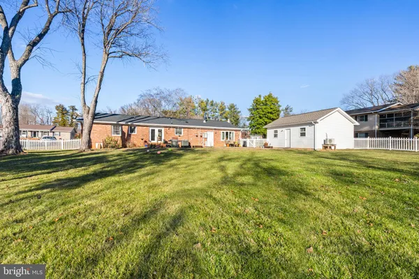 a white house that has a big yard with large trees