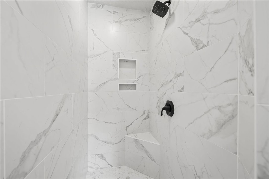 212 Blue Ridge Drive Clemson, SC 29631 - Photo 19 of 33 Marble-look tile lines this generously sized shower, featuring a built-in bench and recessed shelves for convenience.