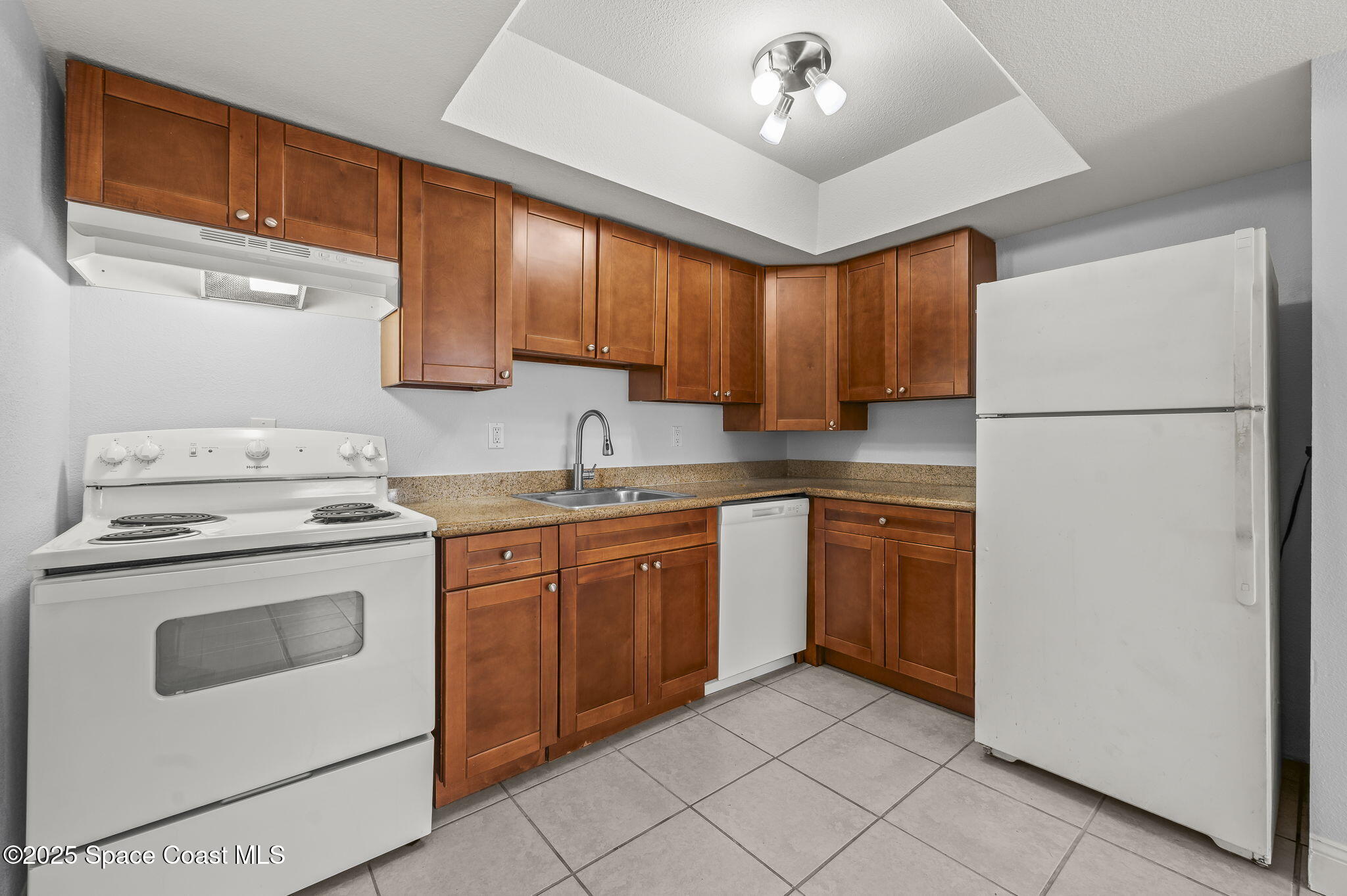1170 South Patrick Drive, Unit 29 Satellite Beach, FL 32937 - Photo 9 of 18 a kitchen with a stove sink and a refrigerator
