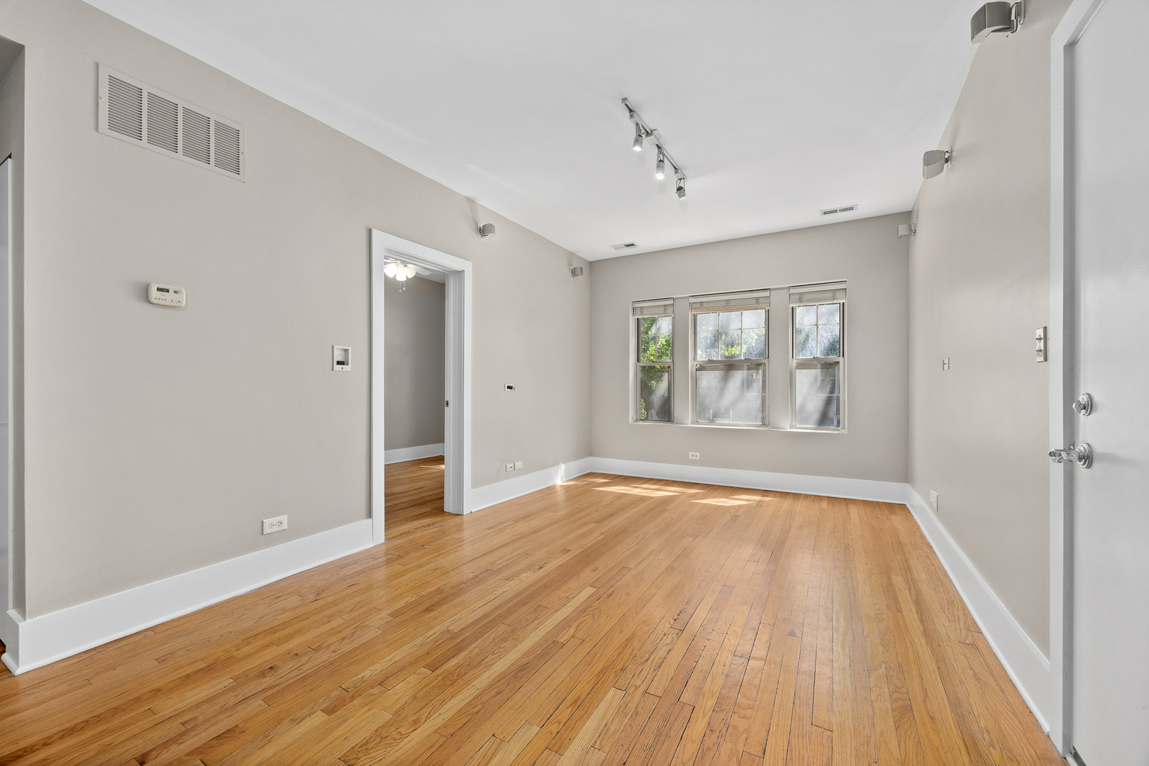 3418 North Wolcott Avenue, Unit 1N Chicago, IL 60657 - Photo 3 of 16 a view of an empty room with wooden floor and a window