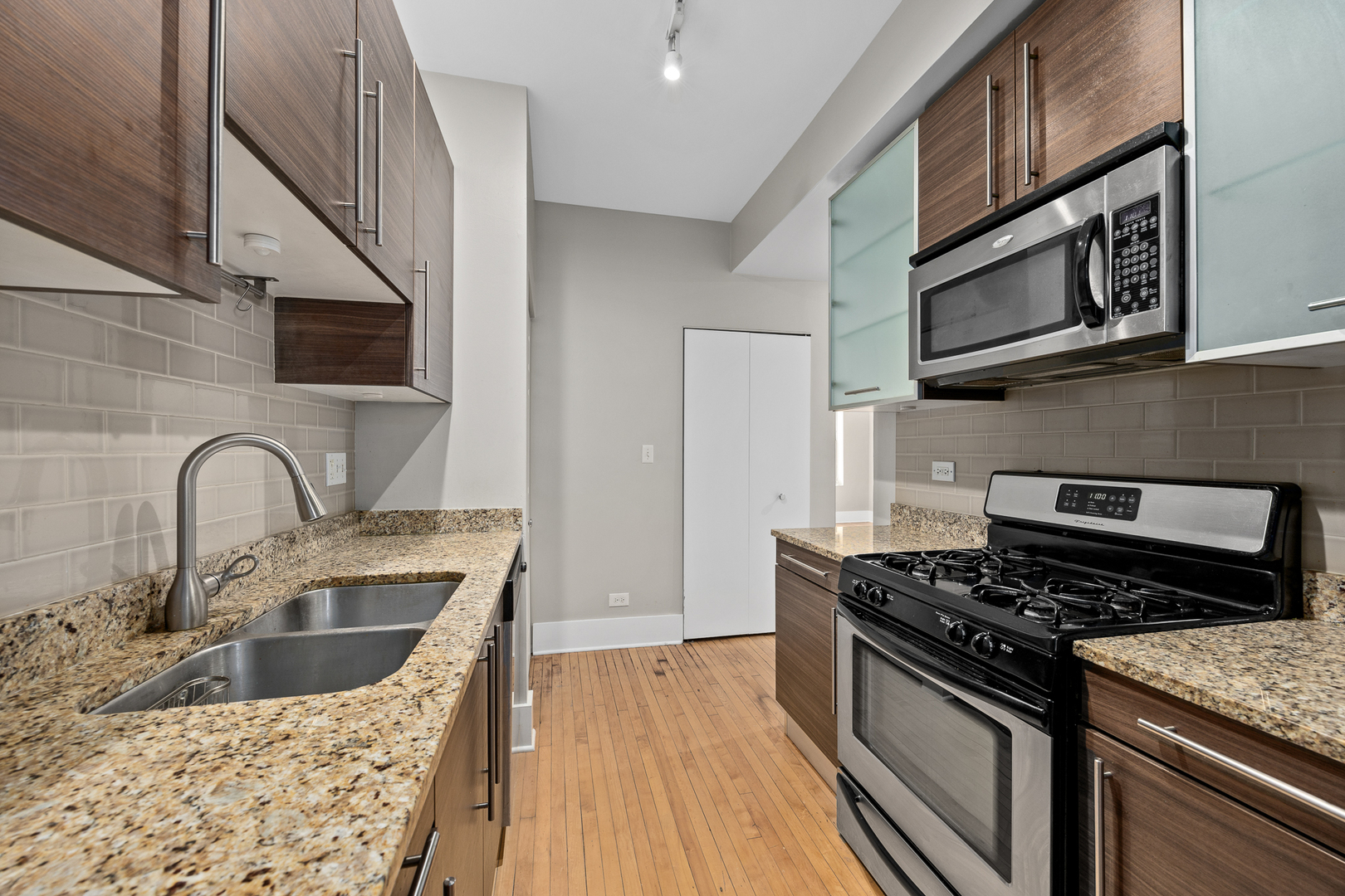 3418 North Wolcott Avenue, Unit 1N Chicago, IL 60657 - Photo 6 of 16 a kitchen with stainless steel appliances granite countertop a sink a stove and a microwave