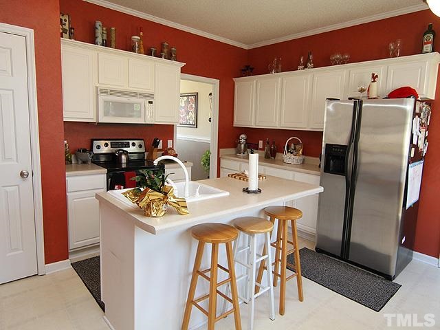 282 Saddle Ridge Drive Willow Spring, NC 27592 - Photo 9 of 23 a kitchen with stainless steel appliances kitchen island a table chairs in it and a microwave