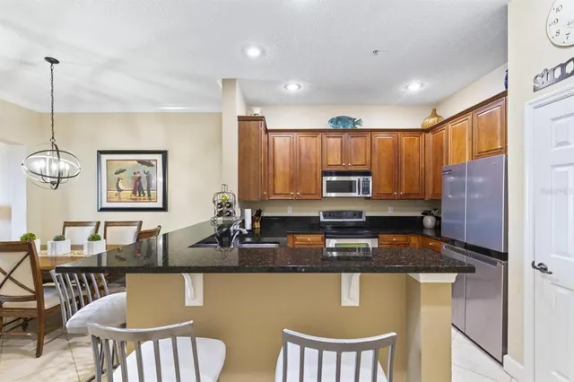 a kitchen with stainless steel appliances granite countertop a table chairs and a refrigerator