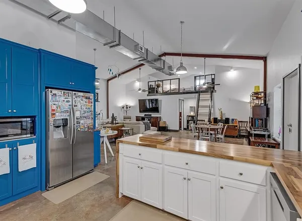 a kitchen with stainless steel appliances kitchen island granite countertop a refrigerator a sink a stove and chairs with wooden floor