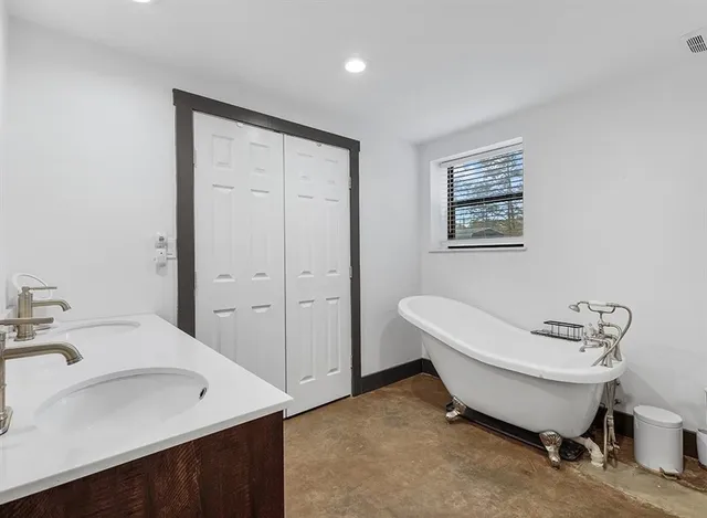 a spacious bathroom with a double vanity sink a mirror and a toilet