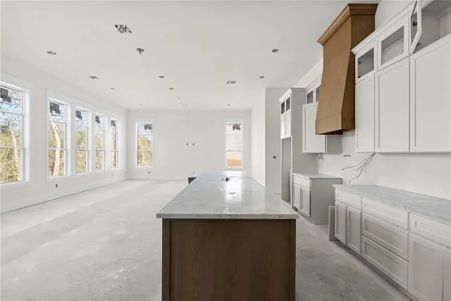 a kitchen with kitchen island granite countertop a sink and white cabinets