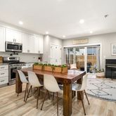 a kitchen with stainless steel appliances granite countertop a stove top oven a sink a dining table and chairs with wooden floor