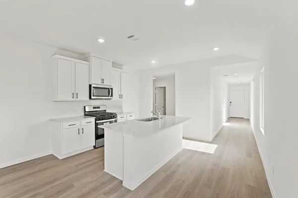 a kitchen with stainless steel appliances a white refrigerator a sink and white cabinets