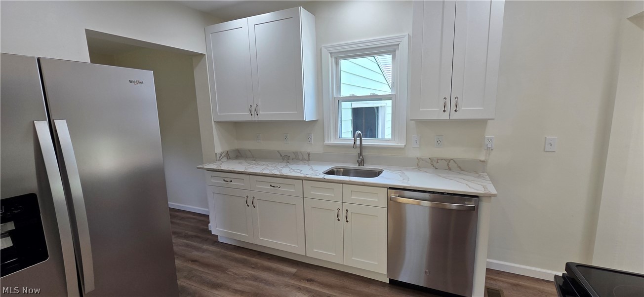 9964 East River Road Elyria, OH 44035 - Photo 13 of 45 Kitchen featuring white shaker cabinetry, new stainless steel appliances, a stainless steel sink, wood-finish flooring, and light-toned quartz countertops