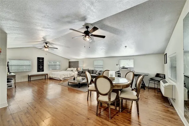 a dining room with wooden floor a chandelier a glass table and chairs