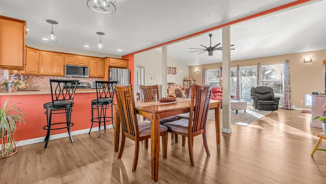 a dining hall with stainless steel appliances a dining table and chairs with wooden floor