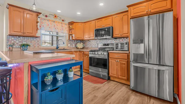 a kitchen with stainless steel appliances granite countertop a refrigerator a stove top oven a sink and dishwasher