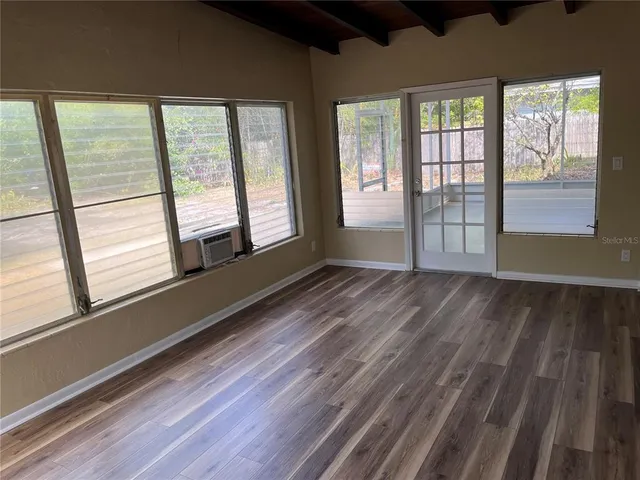 a view of an empty room and wooden floor and windows