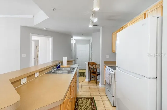 a kitchen with stainless steel appliances granite countertop a sink dishwasher a stove a refrigerator and a dining table with wooden floor