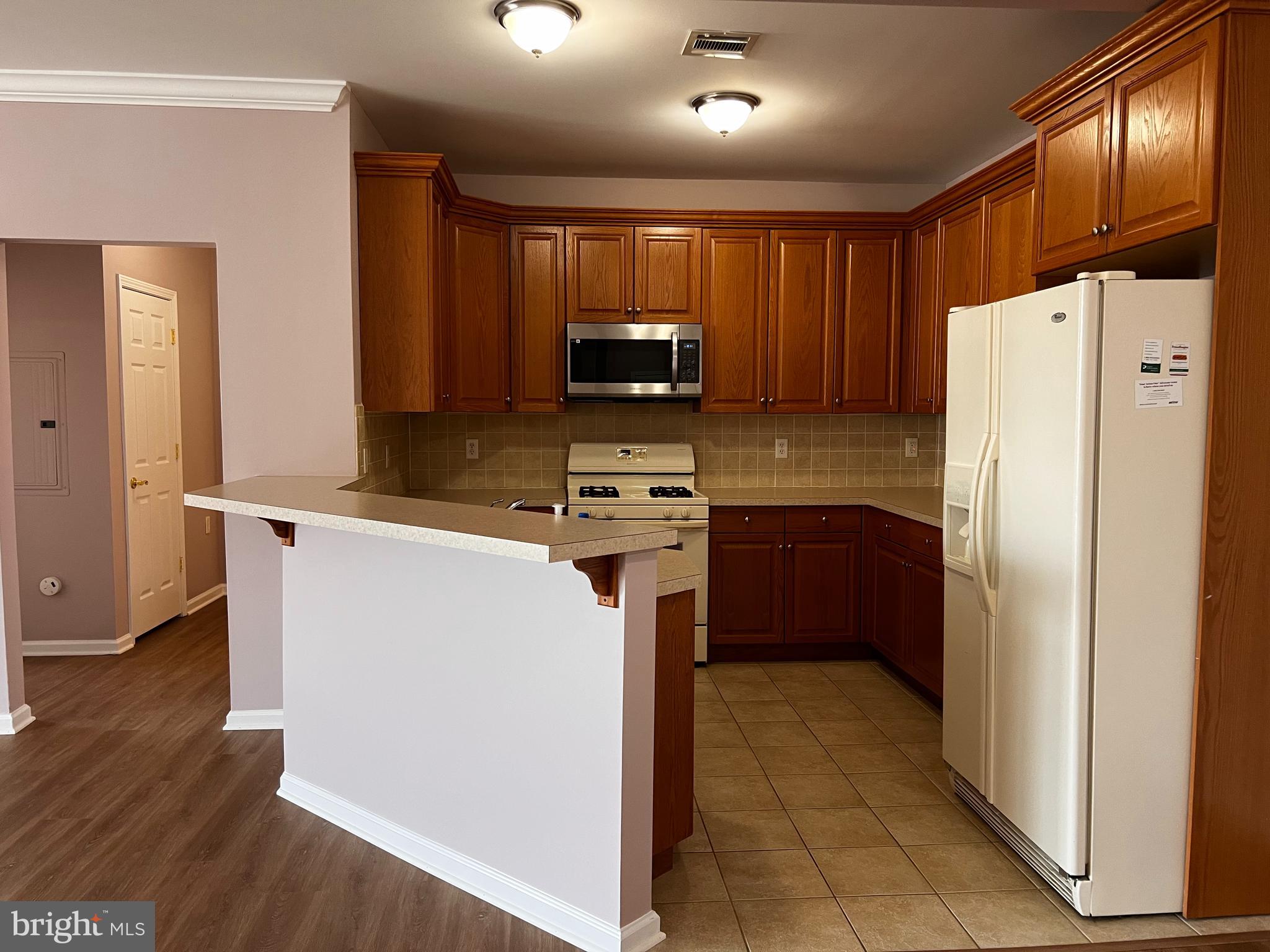 245 Masterson Court Ewing, NJ 08618 - Photo 10 of 25 a kitchen with a refrigerator a stove top oven and wooden floor