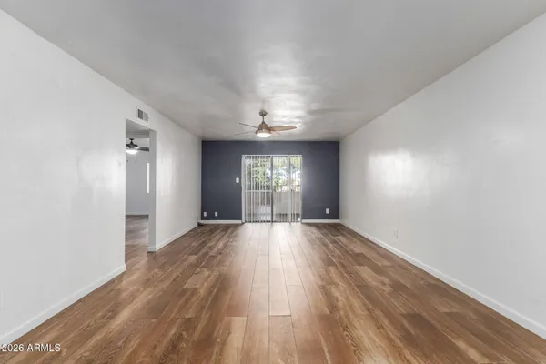 a view of an empty room with wooden floor closet and a window