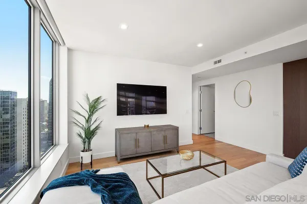 a living room with furniture a flat screen tv and a floor to ceiling window