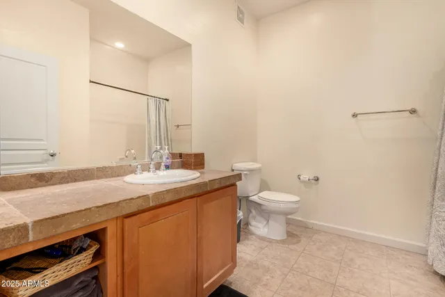 a bathroom with a granite countertop sink toilet and mirror