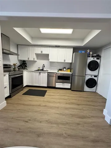 a large kitchen with stainless steel appliances and a wooden floor