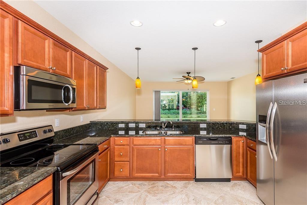 3948 San Rocco Drive, Unit 112 Punta Gorda, FL 33950 - Photo 7 of 18 a kitchen with granite countertop a stove a sink and a microwave