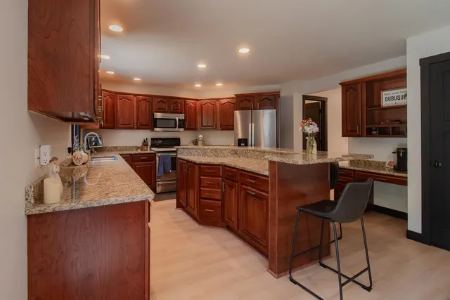 a kitchen with kitchen island a counter top space a sink stainless steel appliances and cabinets