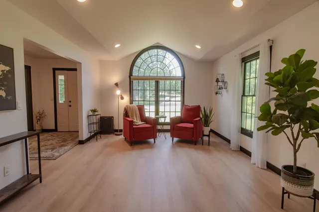 a living room with furniture floor to ceiling window and a potted plant
