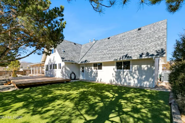 a view of backyard with large tree and wooden fence