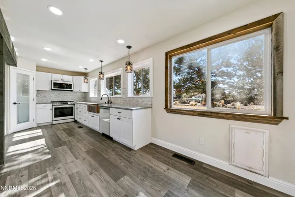 a kitchen with white cabinets stainless steel appliances and window