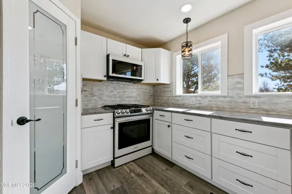 a large kitchen with granite countertop a large window and white stainless steel appliances